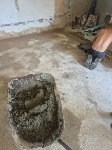 A beton behordása talicskával a régi ház helyiségébe.